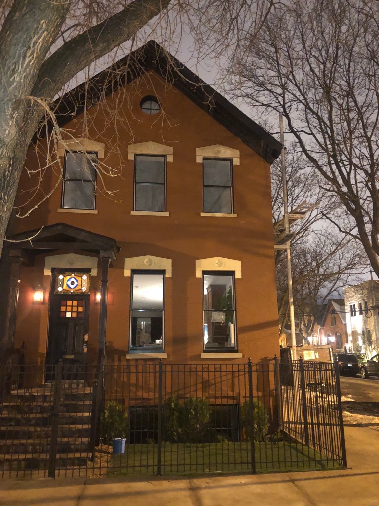 red brick house metal fence black windows stain glass window front porch